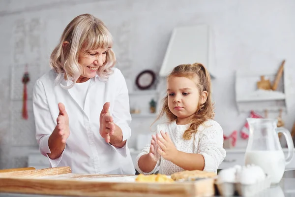 Teaching process. Senior grandmother with her little granddaughter cooks sweets for Christmas on the kitchen.