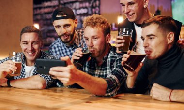 Telefon kullanıyor. Bir grup insan hafta sonları barda eğleniyor..