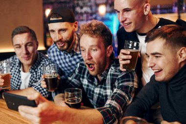 Telefon kullanıyor. Bir grup insan hafta sonları barda eğleniyor..