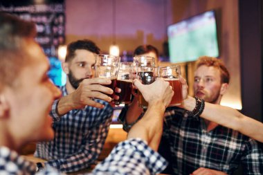 Bira bardaklarına vurarak tezahürat. Bir grup insan hafta sonları barda eğleniyor..