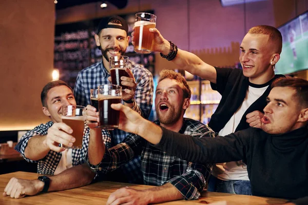 Bira bardaklarına vurarak tezahürat. Bir grup insan hafta sonları barda eğleniyor..