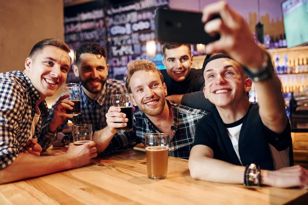 男人通过电话自取灭亡 一群人在酒吧的室内共度周末 玩得很开心 — 图库照片