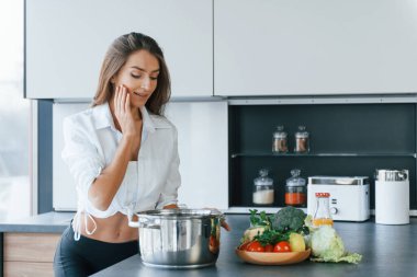 Tabakta yemek hazırlığı. Genç Avrupalı kadın içeride, mutfakta sağlıklı yiyeceklerle birlikte..