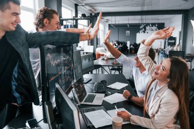 Çak bir beşlik. Borsacılardan oluşan bir ekip modern ofiste birçok ekran ekranı ile çalışır..