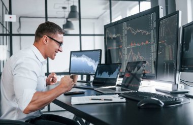 Genç borsacı erkek ofis içinde çalışıyor. Ekranların çoğu.