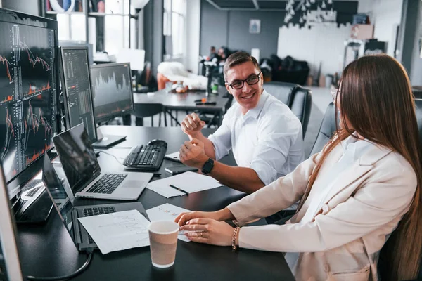 Celebrates success. Team of stockbrokers works in modern office with many display screens.