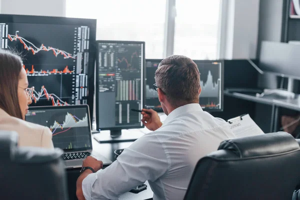 Borsacılardan oluşan bir ekip modern ofiste birçok ekran ekranı ile çalışır..