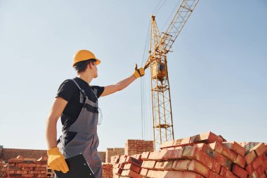 Vinçli adamla iletişim kuruyorum. Üniformalı inşaat işçisi ve güvenlik ekipmanı inşaatında çalışıyor.