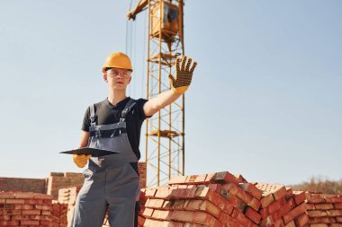 Dur işaretini elle gösterir. Üniformalı inşaat işçisi ve güvenlik ekipmanı inşaatında çalışıyor.