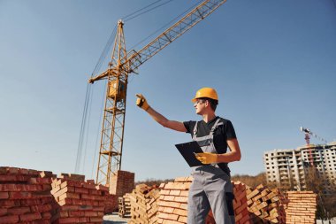 Üniformalı inşaat işçisi ve güvenlik ekipmanı inşaatında çalışıyor.