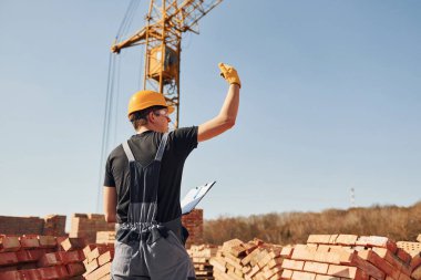 Jestler ve konuşmalar gösteriyor. Üniformalı inşaat işçisi ve güvenlik ekipmanı inşaatında çalışıyor.