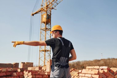 Jestler ve konuşmalar gösteriyor. Üniformalı inşaat işçisi ve güvenlik ekipmanı inşaatında çalışıyor.
