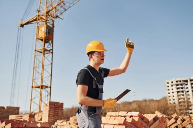 Jestler ve konuşmalar gösteriyor. Üniformalı inşaat işçisi ve güvenlik ekipmanı inşaatında çalışıyor.