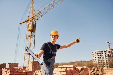 Jestler ve konuşmalar gösteriyor. Üniformalı inşaat işçisi ve güvenlik ekipmanı inşaatında çalışıyor.