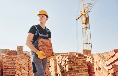Installing brick wall. Construction worker in uniform and safety equipment have job on building.