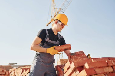 Installing brick wall. Construction worker in uniform and safety equipment have job on building.