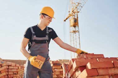 Installing brick wall. Construction worker in uniform and safety equipment have job on building.