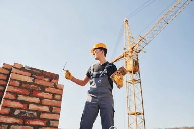 Installing brick wall. Construction worker in uniform and safety equipment have job on building.