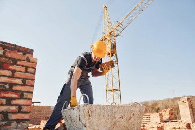 Üniformalı inşaat işçisi ve güvenlik ekipmanı inşaatında çalışıyor.