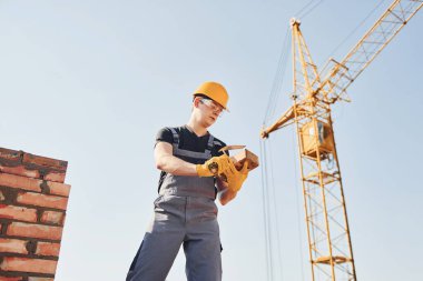 Construction worker in uniform and safety equipment have job on building.