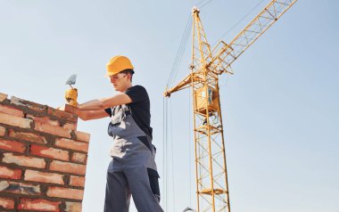 Installing brick wall. Construction worker in uniform and safety equipment have job on building.