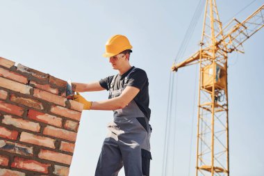 Installing brick wall. Construction worker in uniform and safety equipment have job on building.