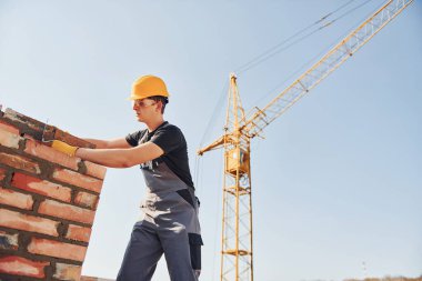 Installing brick wall. Construction worker in uniform and safety equipment have job on building.