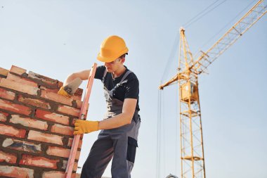 Installing brick wall. Construction worker in uniform and safety equipment have job on building.