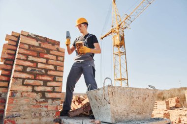 Tuğla duvar kuruluyor. Üniformalı inşaat işçisi ve güvenlik ekipmanı inşaatında çalışıyor.