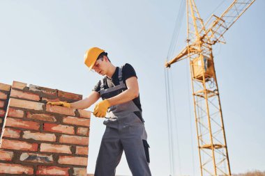 Installing brick wall. Construction worker in uniform and safety equipment have job on building.