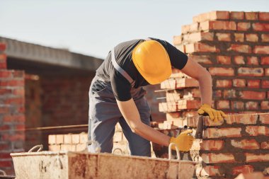 Busy with brick wall. Construction worker in uniform and safety equipment have job on building.