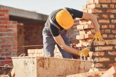 Busy with brick wall. Construction worker in uniform and safety equipment have job on building.