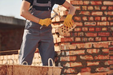 Busy with brick wall. Construction worker in uniform and safety equipment have job on building.