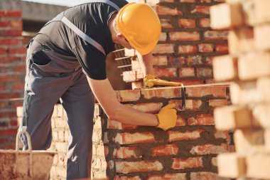 Busy with brick wall. Construction worker in uniform and safety equipment have job on building.