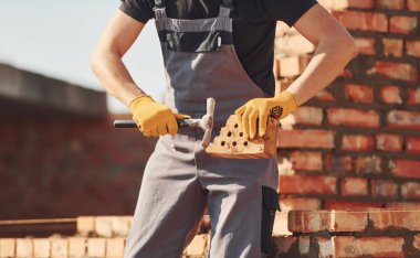 Tuğla duvarla meşgul. Üniformalı inşaat işçisi ve güvenlik ekipmanı inşaatında çalışıyor.