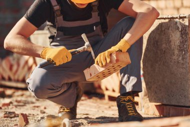 Construction worker in uniform and safety equipment sits and have job on building.