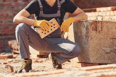Construction worker in uniform and safety equipment sits and have job on building.