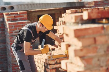 Measures of brick wall. Construction worker in uniform and safety equipment have job on building.