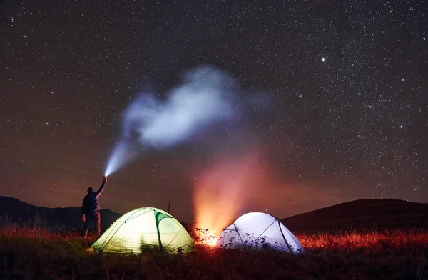 Man Holds Device Light Beam Two Iluminated Tents Campfire Stars — Fotografia de Stock