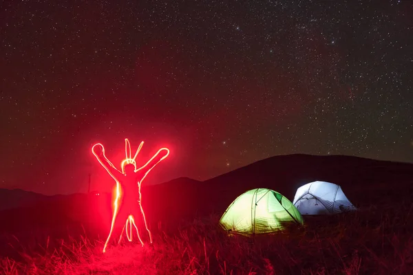 Figure Man Neon Lighting Two Iluminated Tents Stars Mountains Night — Fotografia de Stock