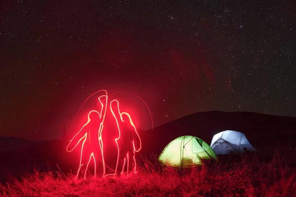 Фигуры Людей Неоновом Освещении Две Освещенные Палатки Звездами Горах Ночью — стоковое фото