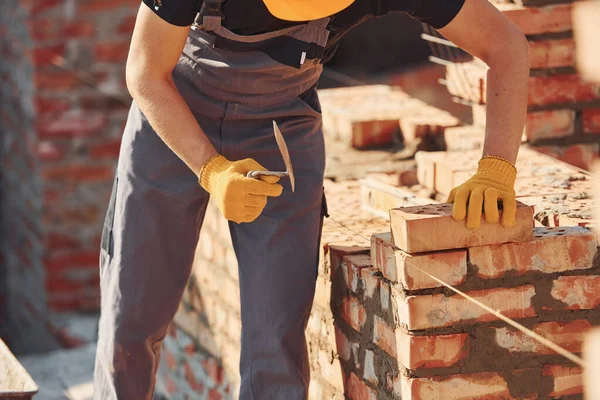 Measures of brick wall. Construction worker in uniform and safety equipment have job on building.
