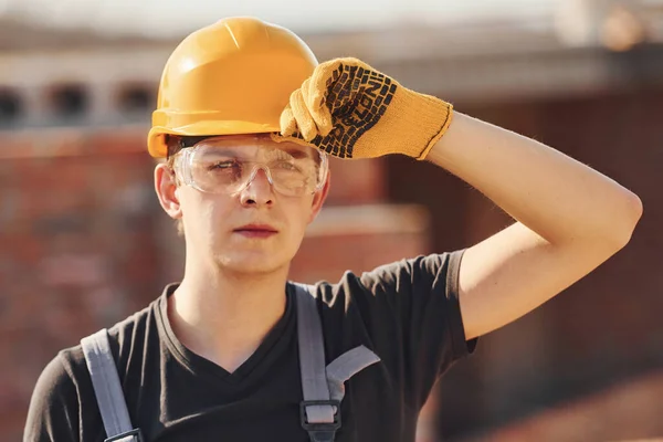Portrait of construction worker in uniform and safety equipment that standing on building.