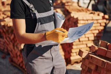 Planı kontrol altında tutuyoruz. Üniformalı inşaat işçisi ve güvenlik ekipmanı inşaatında çalışıyor.