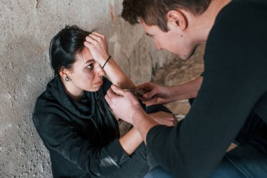 Kaçırılan kadın oturuyor ve terk edilmiş binada elinde bıçakla bir adam tarafından tehdit ediliyor..