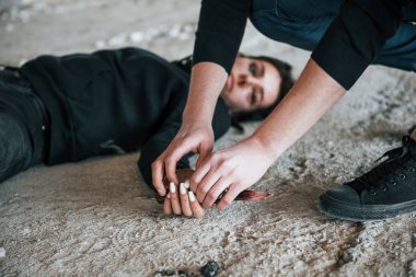 Katil elinde bıçakla kana bulanmış halde ölü genç kurbanının yanında oturuyor..