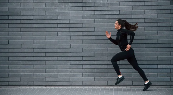 Young Sportive Girl Black Sportswear Running Outdoors Gray Wall — Stockfoto
