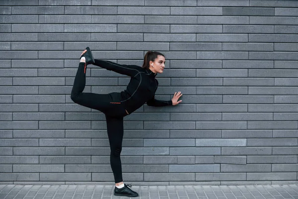 Young Sportive Girl Black Sportswear Outdoors Doing Yoga Exercises Gray — Zdjęcie stockowe