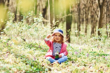 Mavi şapkalı mutlu küçük kız bahar ormanlarında gündüz vakti yürüyor..