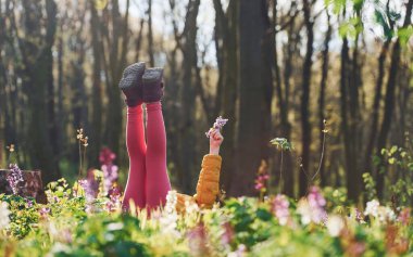 Gündüz vakti Bahar Ormanı 'nda yerde uzanan günlük giysiler içinde mutlu küçük kız..